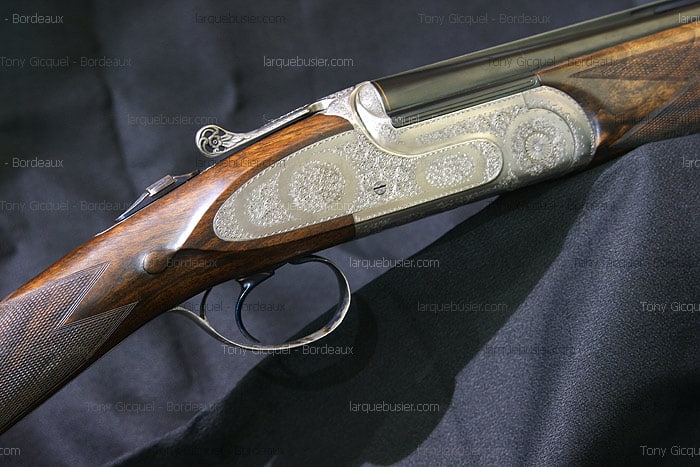 Détail d'un fusil de chasse superposé de luxe, gravé avec motifs floraux, bois travaillé. Watermark larquebusier.com Tony Gicquel Bordeaux.