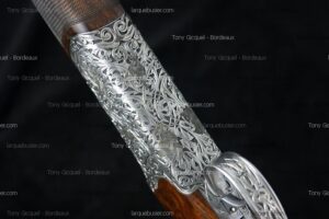 Boîtier de culasse de fusil de chasse finement gravé de rinceaux argentés et motifs cynégétiques. Crosse bois. Tony Gicquel - Bordeaux, larquebusier.com.