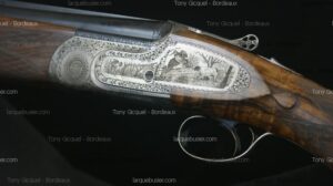 Fusil de chasse haut de gamme, receveur gravé d'oiseaux et d'arbres sur fond de bois. Mentions "Tony Gicquel - Bordeaux", "larquebusier.com".