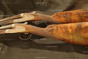 Deux fusils de chasse juxtaposés, gravures fines et crosses en bois de noyer figuré. Filigranes Tony Gicquel - Bordeaux et larquebusier.com.
