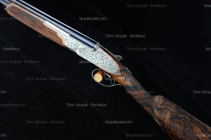 Fusil superposé avec crosse en noyer figuré, boîtier gravé et détente dorée. Marques Tony Gicquel - Bordeaux, larquebusier.com.