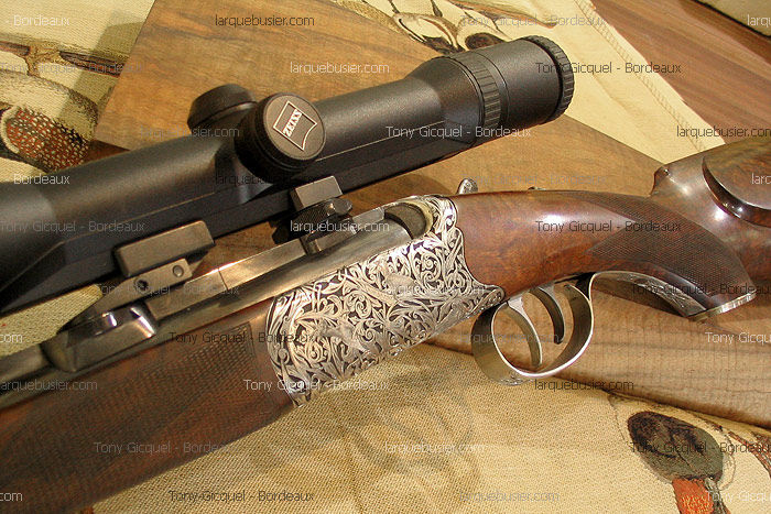 Fusil de chasse de luxe en bois, avec culasse gravée de motifs floraux et gibiers, équipé d'une lunette de visée Zeiss.