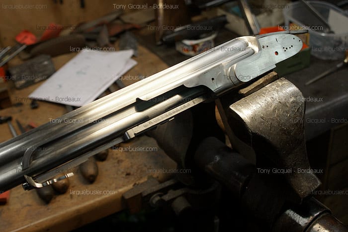 Action de fusil en métal brut, double canon, serrée dans un étau d'atelier. Fabrication artisanale d'armes par Tony Gicquel à Bordeaux.