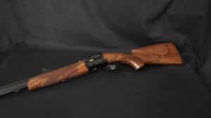 Carabine de chasse en bois de noyer gravé et métal noir sur fond sombre. Détails du quadrillage sur crosse et devant, inscription 'GIRARDCA'.