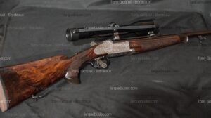 Carabine express de chasse haut de gamme avec crosse en bois veiné, gravures détaillées sur le boîtier et lunette. Marquage Tony Gicquel - Bordeaux, larquebusier.com.