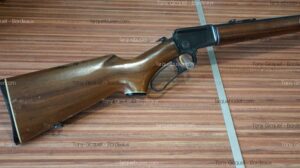 Carabine à levier de sous-garde, crosse et garde-main en bois foncé, mécanisme noir, sur fond bois. Texte: Tony Gicquel - Bordeaux, larquebusier.com.