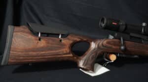 Carabine de tir avec crosse bois stratifié marron, appuie-joue réglable et lunette de visée Minox. Poignée pistolet ajourée.