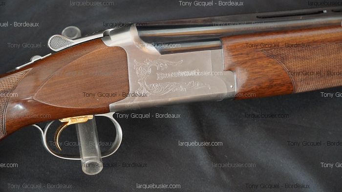Fusil de chasse Browning superposé en bois et métal. Crosse et devant quadrillés, bascule gravée, détente dorée. Marque Browning.