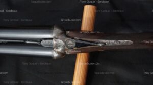 Fusil de chasse double canon, vue de dessus, avec culasse finement gravée et crosse en bois. Marques Tony Gicquel - Bordeaux, larquebusier.com.