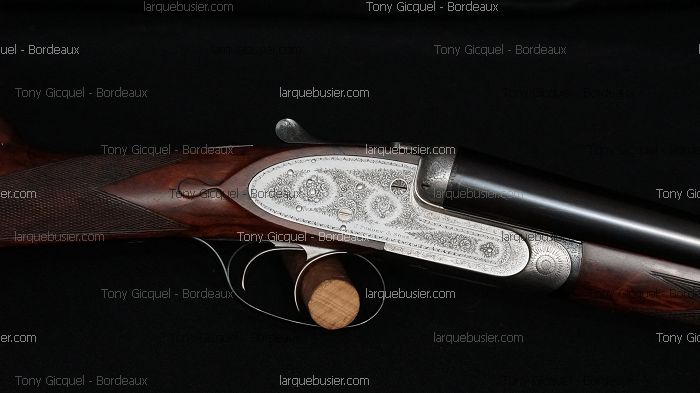 Vue latérale d'un fusil de chasse double, action finement gravée et crosse en bois foncé. Tony Gicquel - Bordeaux, larquebusier.com.