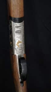 Fusil de chasse FAIR Classic. Récepteur argenté richement gravé de motifs floraux et canards dorés. Crosse en bois veiné foncé. Inscriptions: FAIR, Classic.