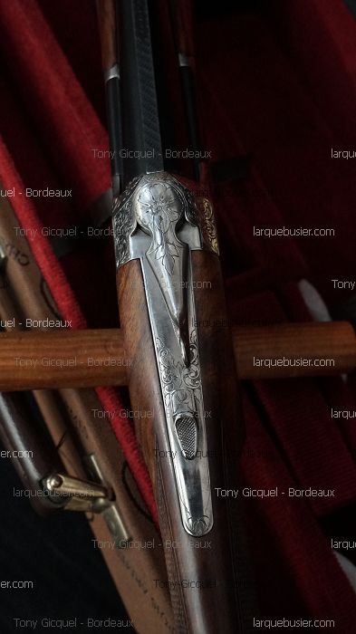 Détail d'un fusil de chasse superposé gravé, crosse en bois, dans étui velours rouge. Tony Gicquel - Bordeaux, larquebusier.com.