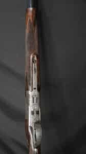 Fusil de chasse en bois précieux, détail du quadrillage et de la bascule en métal finement gravé de motifs floraux.