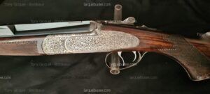 Fusil de chasse avec boîtier finement gravé de motifs floraux, crosse en bois quadrillée, doubles détentes. Tony Gicquel - Bordeaux, larquebusier.com.