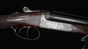 Fusil de chasse Tony Gigliel, bascule gravée de deux faisans en vol et volutes florales. Crosse en bois foncé. Art armurier raffiné.