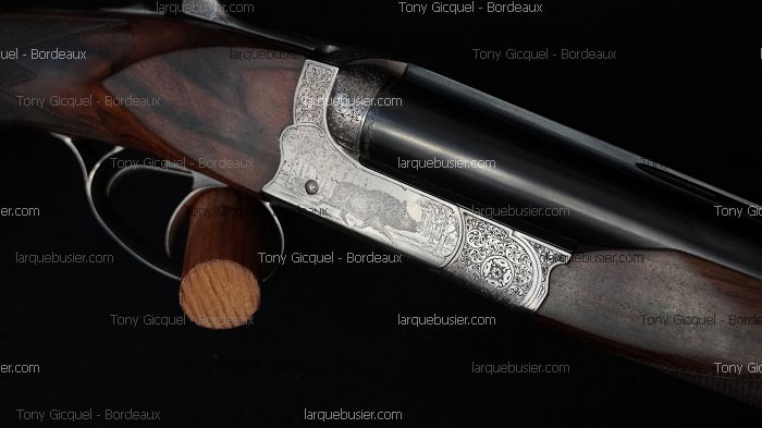 Fusil de chasse luxe, platine gravée sanglier et motifs floraux. Crosse bois sombre, canons. Watermarks : Tony Gicquel - Bordeaux, larquebusier.com.