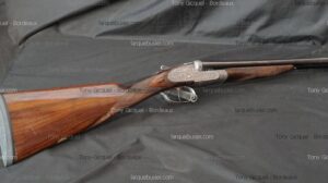 Fusil de chasse juxtaposé ancien à crosse bois sculptée, bascule finement gravée. Marqué "Tony Gicquel - Bordeaux" et "larquebusier.com".