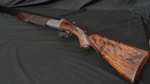 Fusil de chasse superposé de luxe avec crosse en noyer figuré et bascule en métal finement gravé de motifs floraux.