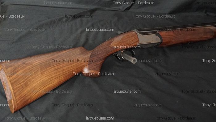 Fusil de chasse superposé, crosse en bois veiné et métal, posé sur fond sombre. Texte visible : Tony Gicquel - Bordeaux, larquebusier.com.