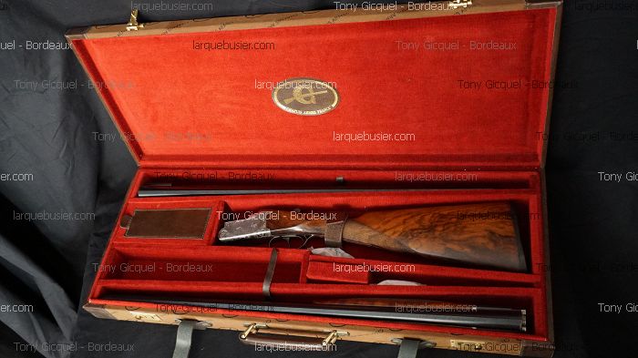 Élégant fusil de chasse à double canon démonté dans son étui en bois ouvert avec intérieur velours rouge. Plaque 'larquebusier.com'.