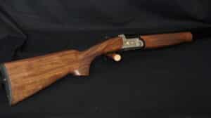 Fusil de chasse superposé en bois avec gravures dorées d'oiseaux et texte 'DUO VAL' sur le boîtier de culasse argenté.