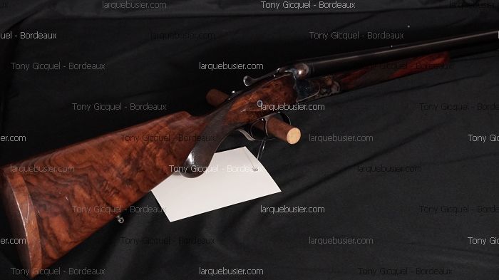Fusil de chasse ou carabine de luxe avec crosse en bois de noyer veiné, posé sur fond noir. Vendu par Tony Gicquel - Bordeaux sur larquebusier.com.