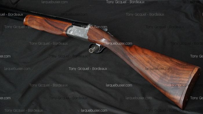 Fusil de chasse superposé avec crosse et devant en bois de noyer richement veiné. Bascule gravée. Tony Gicquel - Bordeaux.