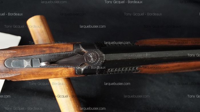 Détail d'un fusil de chasse en bois et acier bronzé avec gravure sur le boîtier. Visible : Tony Gicquel - Bordeaux, larquebusier.com.