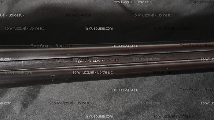 Gros plan sur deux canons de fusil superposés, avec l'inscription gravée en or 'GASTINNE-RENETTE A PARIS' sur le dessus.