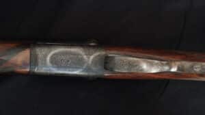 Fusil de chasse ciselé, récepteur métallique finement gravé de motifs floraux et volutes sur bois.