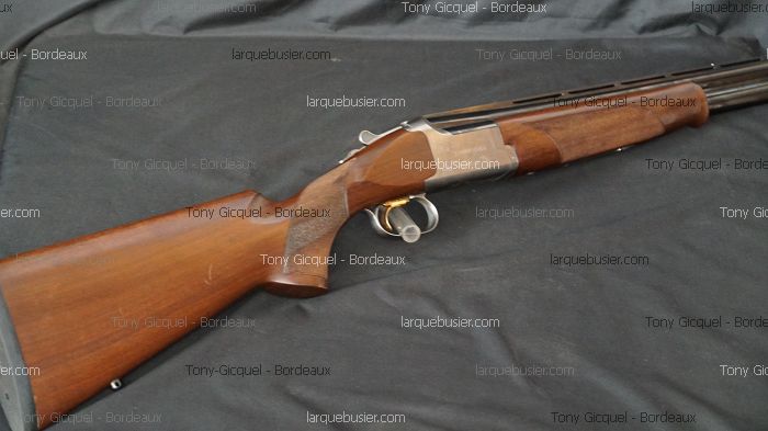 Fusil de chasse superposé à crosse bois et pontet doré, posé sur un tissu sombre. Marquages Tony Gicquel - Bordeaux et larquebusier.com.
