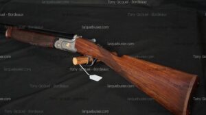 Fusil superposé de chasse avec crosse bois veiné, bascule métal gravée feuille dorée. Marque Tony Gicquel - Bordeaux, larquebusier.com.